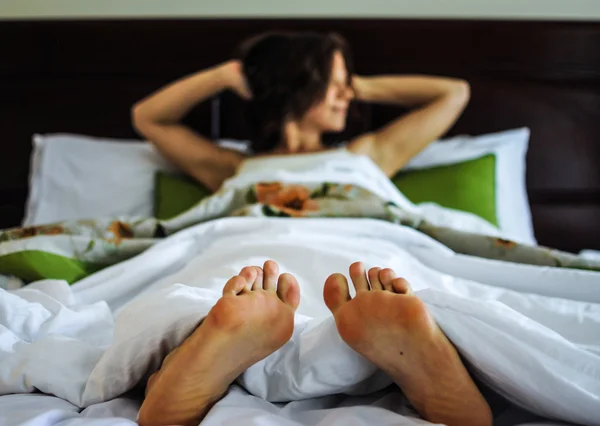Young woman lying in bed and waking up, feet close up