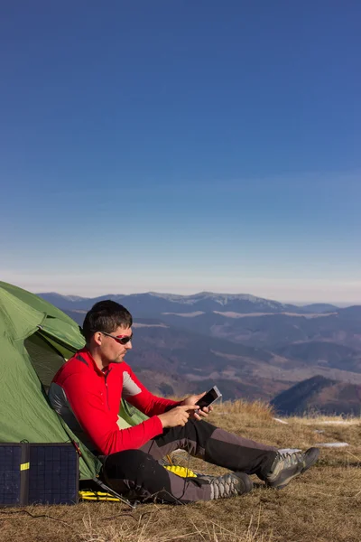 The guy in the mountains, hike with a backpack, and a solar panel for charging accumulators.