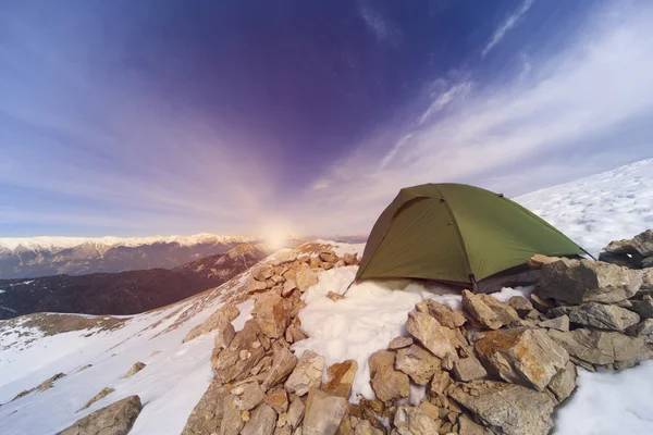 Winter camping in the mountains with a backpack and tent.