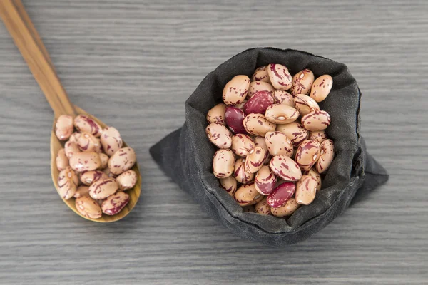 Pinto beans scattered on raw canvas bag