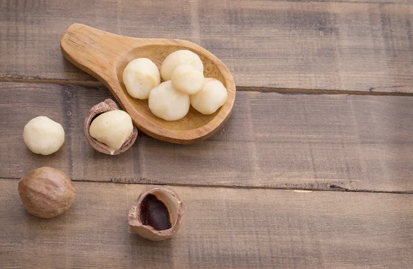 Macadamia on the table and wooden spoon.