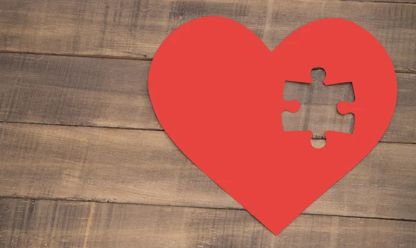 Incomplete puzzle in the shape of a heart on the wooden background