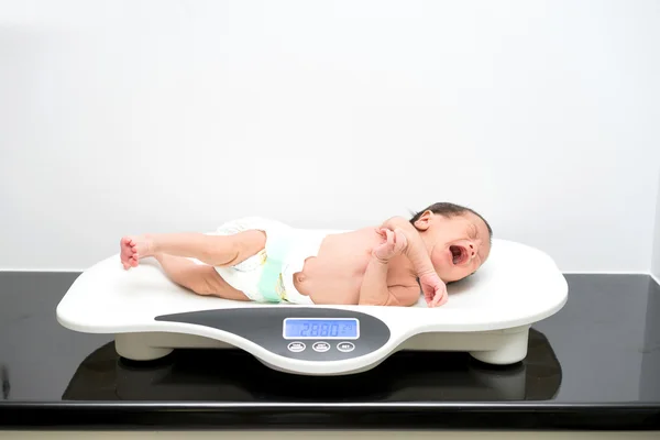 Asian newborn baby laying on the scales