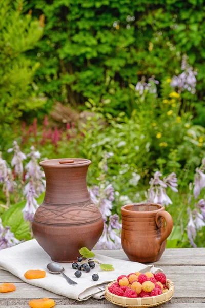 Raspberries in the basket. Clay dishes. In the garden.