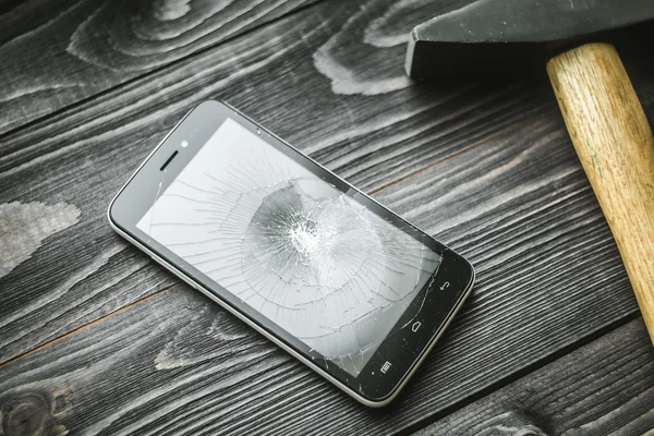 Smartphone with broken display on the wooden rustic background