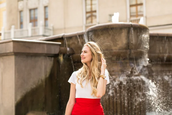 Happy Young woman with long hair standing near  fountain