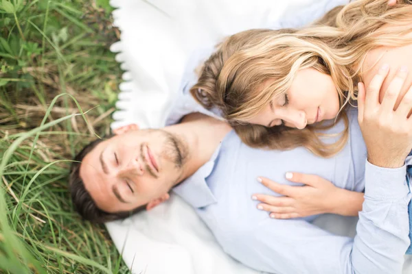 Young couple man and woman lie on the rug on nature, the concept