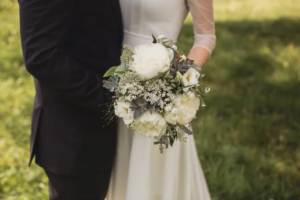 Bride and groom holding a bouquet for a walk