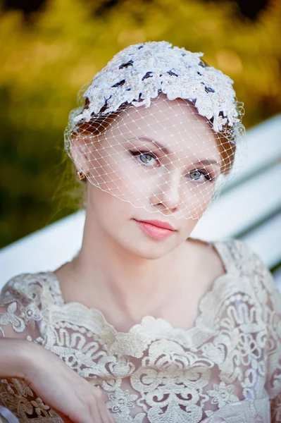 Beautiful blonde with a hairstyle and veil sitting on bench, romantic looks