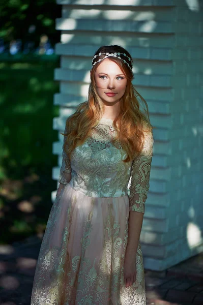 Girl in bright lace dress stands in the shade of the trees, the light falls on the face. The spot