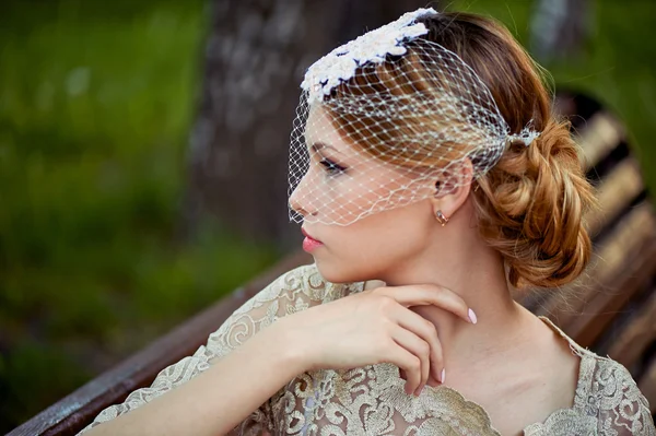 Beautiful blonde with a hairstyle and veil sitting on bench, romantic looks