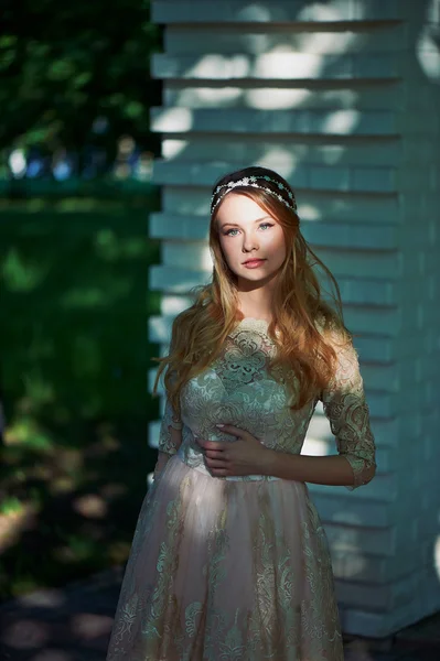 Girl in bright lace dress stands in the shade of the trees, the light falls on the face. The spot