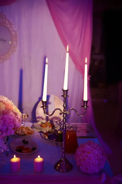 Chandelier with three long white candles. Wedding