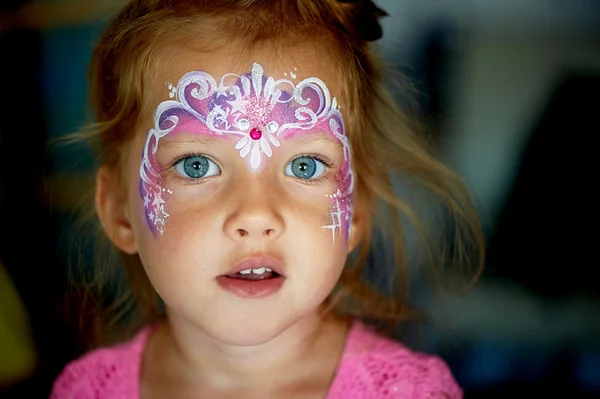 Pretty exciting blue-eyed girl of 2 years with a face painting