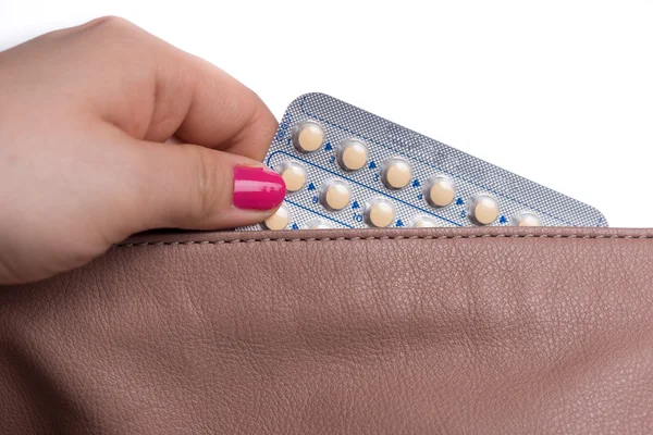 Young woman hand pulling a contraceptive pills blister from a  l