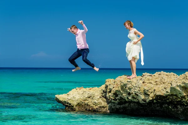 A wedding couple jumping into the ocean