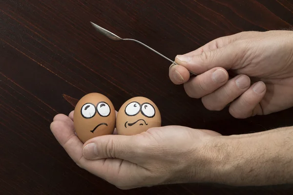 Frightened egg face in man hand and spoon