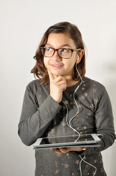 Ingenious girl with tablet in hand. Child with headphones thinking. Latin girl planning something in her mind. Latin girl intellectual.