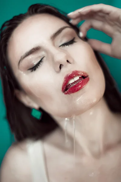 Close-up of beautiful wet woman face with water drop. On green b