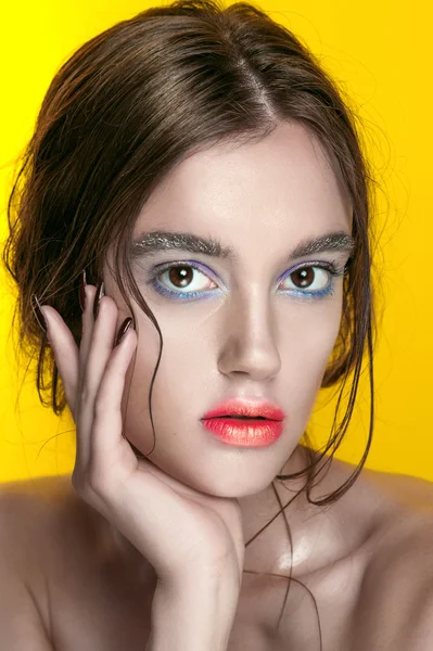 Beauty Girl Portrait with Vivid Makeup. Fashion Woman portrait close up on yellow background. Bright Colors. Manicure Make up. Smoky eyes, long eyelashes. Rainbow Colors. Retouched shot
