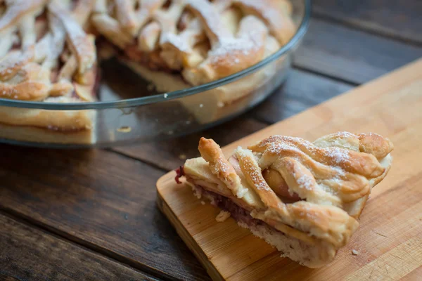 Uncooked homemade rustic apple pie preparation greased with egg yolk on wooden kitchen background