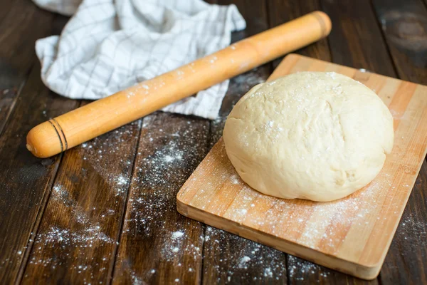 Ball of dough on a rustic wooden background with dusting of flour