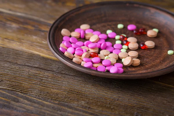 Pills on a plate on a wooden background