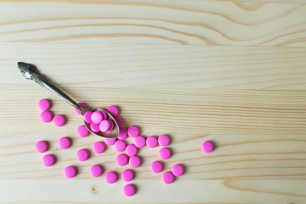 Pharmacy background. Full spoon of pills on a wooden table. Medicine. Natural background. Capsule on a spoon. Close up
