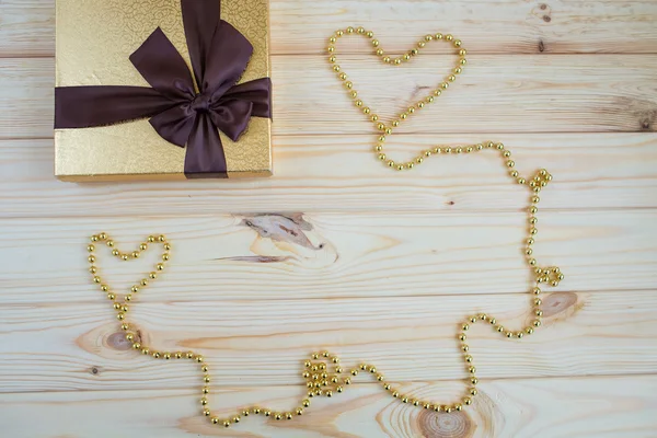 Gift in gold box with a bow on a wooden background