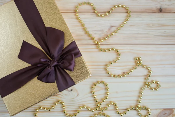 Gift in gold box with a bow on a wooden background