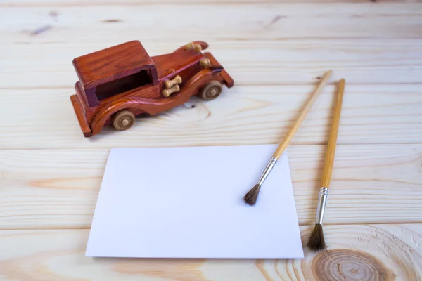 Wooden toy car and a brush to paint on the wooden background