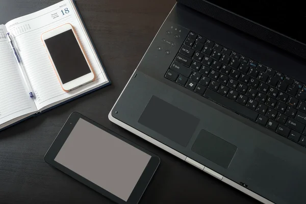 Laptop, tablet, mobile phone, notebook, lying on a black table