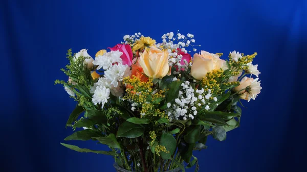 Bouquet of flowers in glass vase on dark blue background