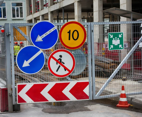 Group of road traffic signs on the metal gate of the constructio