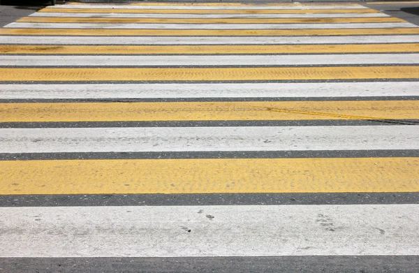 White and yellow lines pedestrian crossing on asphalt closeup in