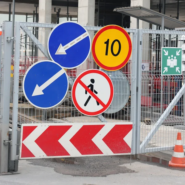 Group of road traffic signs on the metal gate of the constructio