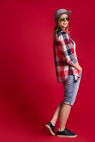 Fashion young woman in a baseball cap and checkered shirt.