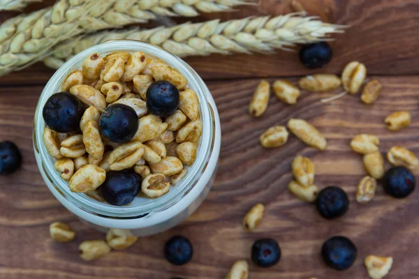 Homemade Yogurt with cereal and berries. Healthy food. Brown wooden background.