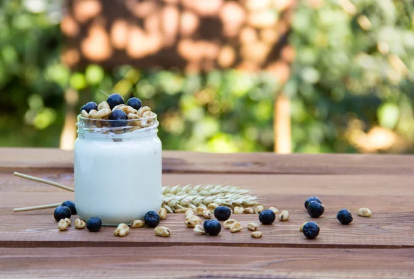 Healthy homemade yogurt with cereals and blue berries. Wooden background. Wheat ears. Homemade food. Copy space