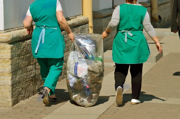 Women carry away the garbage.