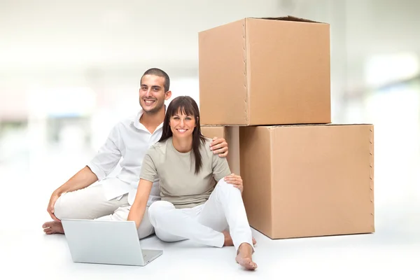 Beautiful young love couple with box and laptop  in a interior design