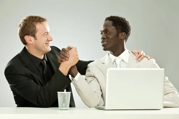 Black and white businessman interracial teamwork with laptop isolated on grey