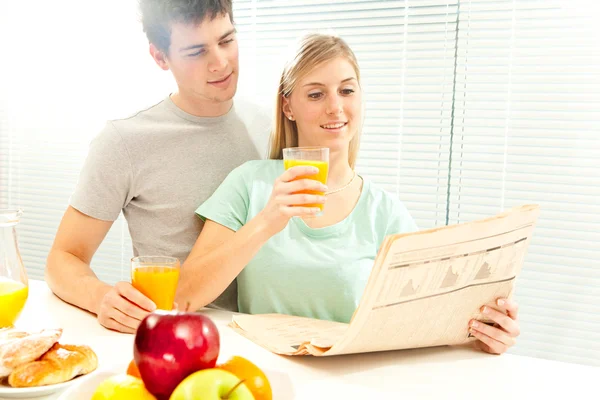 Young casual couple have breakfast with coffee and fruit with venetian blind window