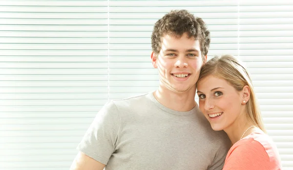 Young casual couple in love with venetian blind window background