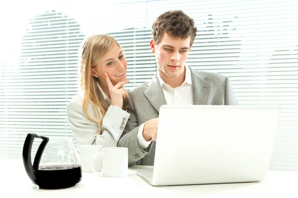 Young business couple work with coffee and laptop with venetian blind window background
