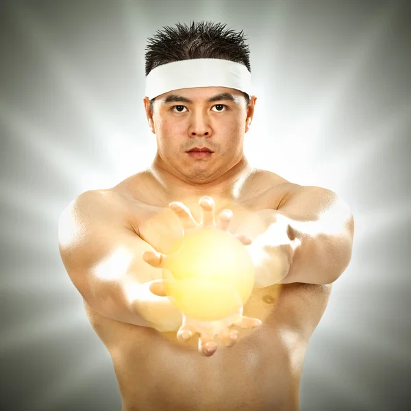 Asian body builder with energy in his hands on grey background