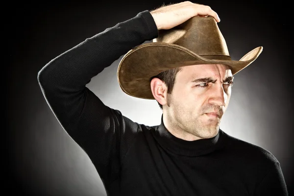 Serious man with cowboy hat portrait on grey background