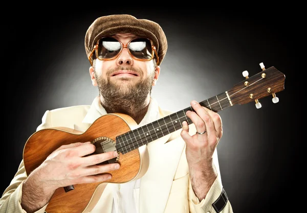 Funny man with glasses play guitar ukelele on black background