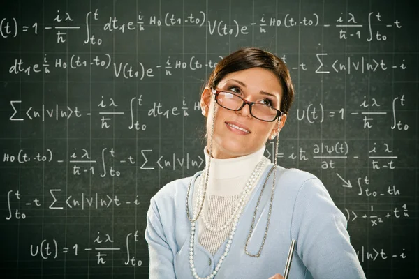 Beautiful smiling young teacher with glasses and blackbouard