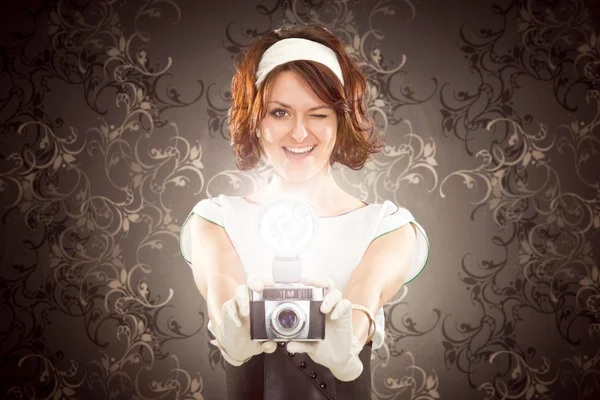 Beautiful vintage girl take photograph with old camera on tapestry background